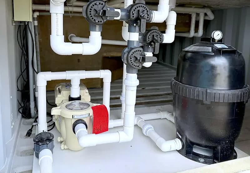 Equipment bay inside a ReadyPool container with the pump, cartridge filter, valves and white PVC plumbing