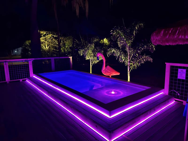 ReadyPool at night glowing blue, with purple strip lighting along the deck steps
