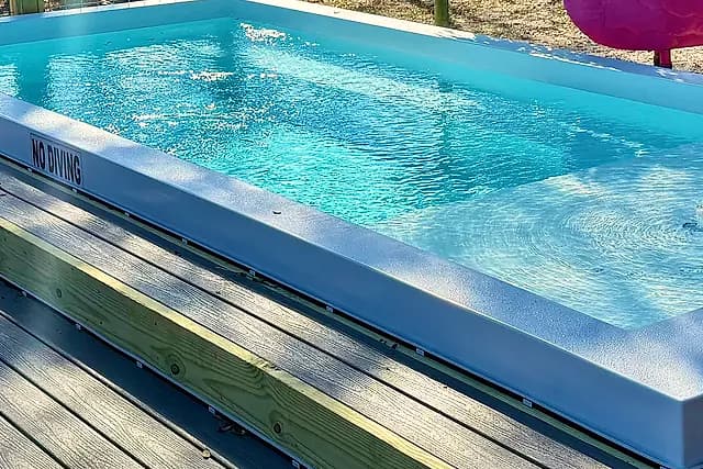 Smooth white fiberglass pool interior and wide coping edge in sunlight